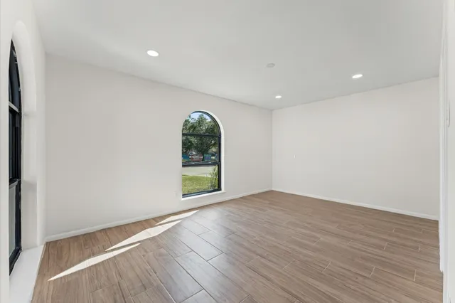 a view of an empty room with wooden floor and a window