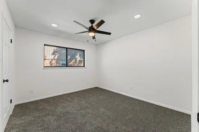 an empty room with a window and a fan