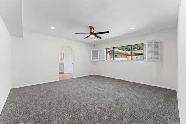 an empty room with ceiling fan and windows