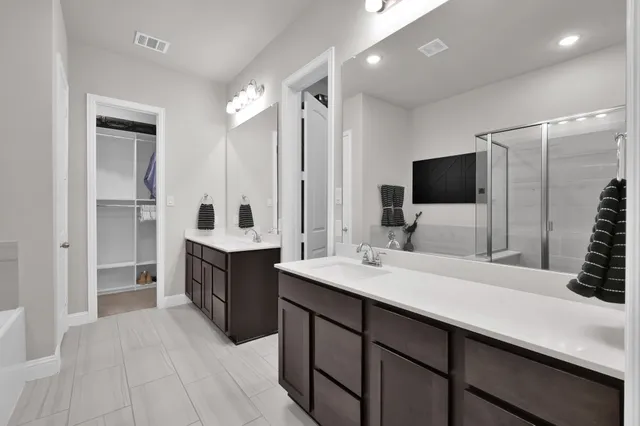 a spacious bathroom with a double vanity sink a mirror and a shower