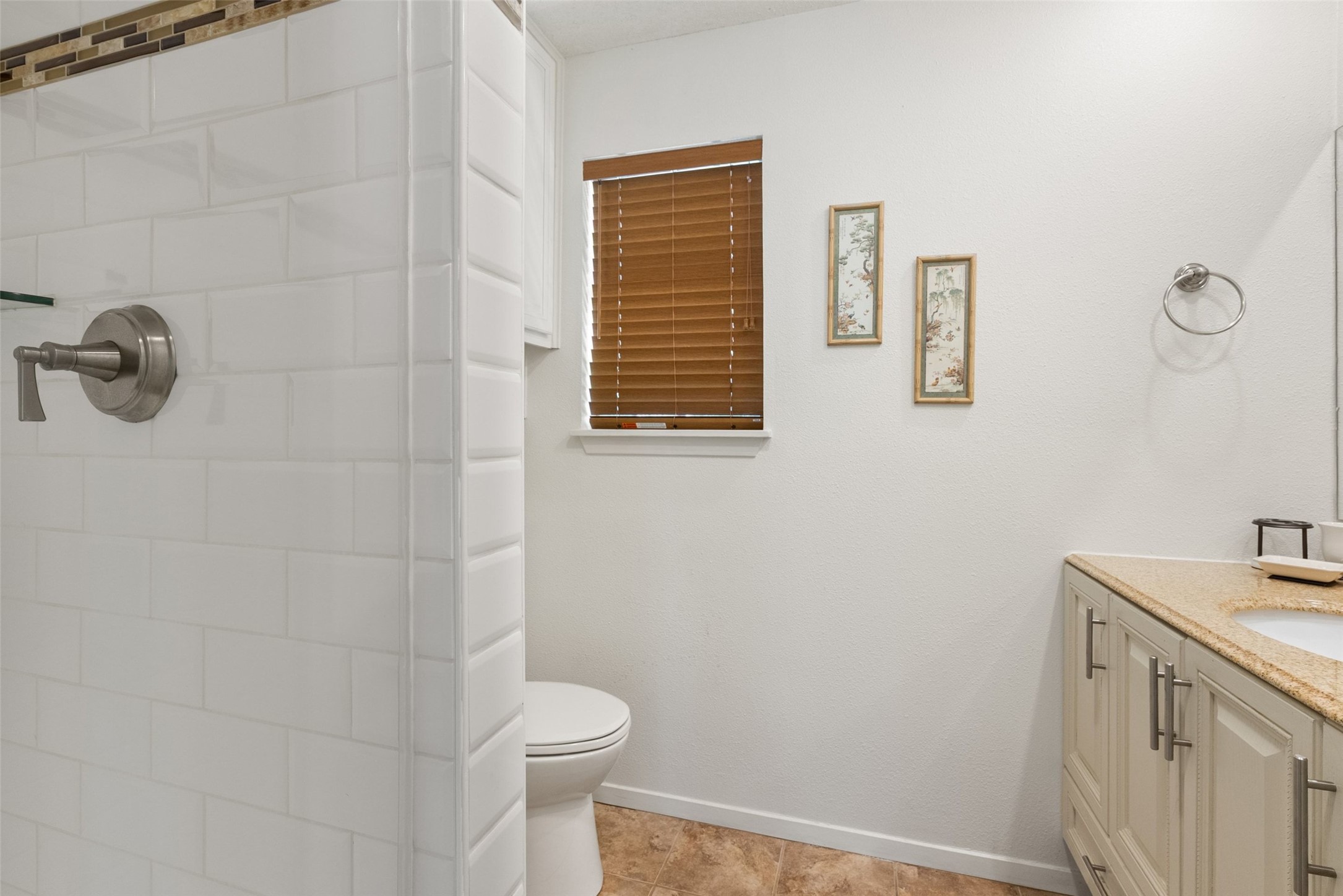141 Perry Lane Kingsland, TX 78639 - Photo 36 of 40 Functional bathroom featuring a tiled shower, a window with blinds, and a vanity with a counter.
