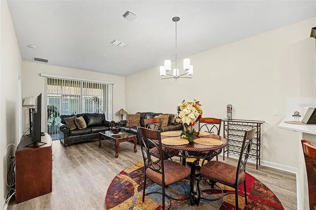 a view of a livingroom and dining room with furniture wooden floor a chandelier