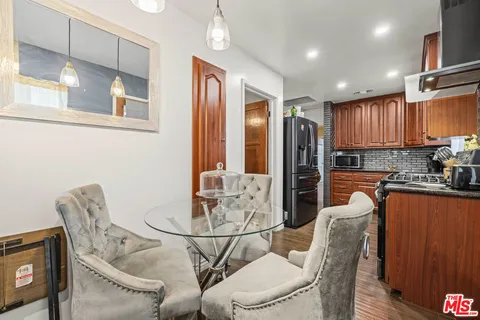 a kitchen with stainless steel appliances granite countertop a dining table chairs and a refrigerator