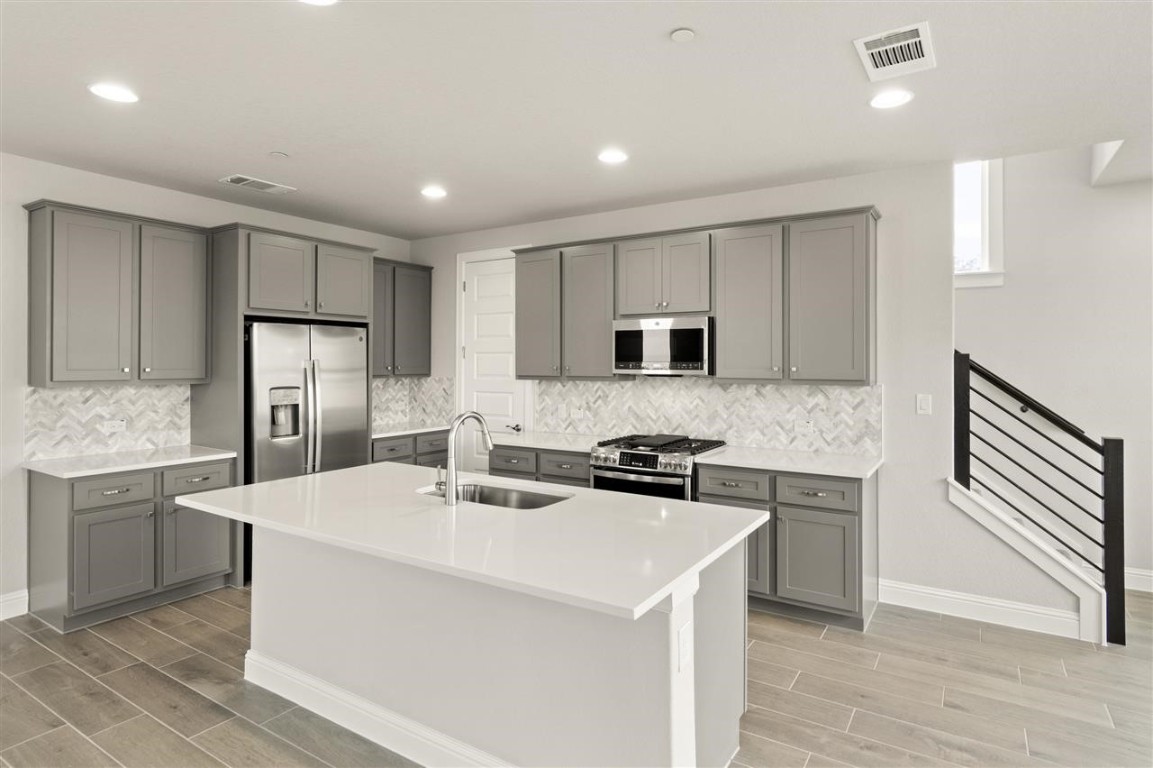 a kitchen with stainless steel appliances a stove sink microwave and cabinets