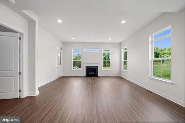 an empty room with wooden floor fireplace and windows