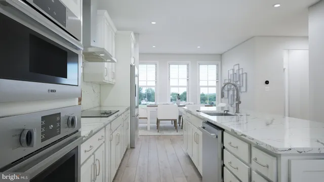 a large kitchen with stainless steel appliances a sink dishwasher a stove a refrigerator and a kitchen island with wooden floor