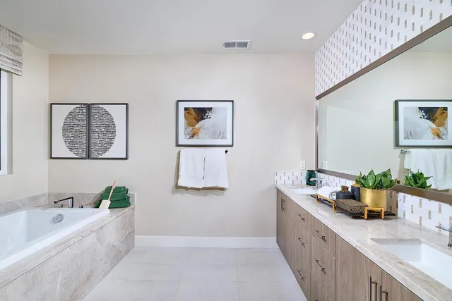 a spacious bathroom with stainless steel appliances a bathtub a sink and a potted plant