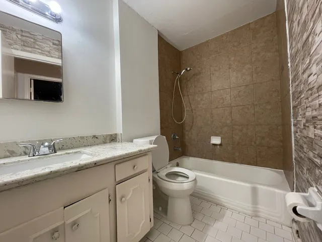 a bathroom with a granite countertop sink toilet and shower