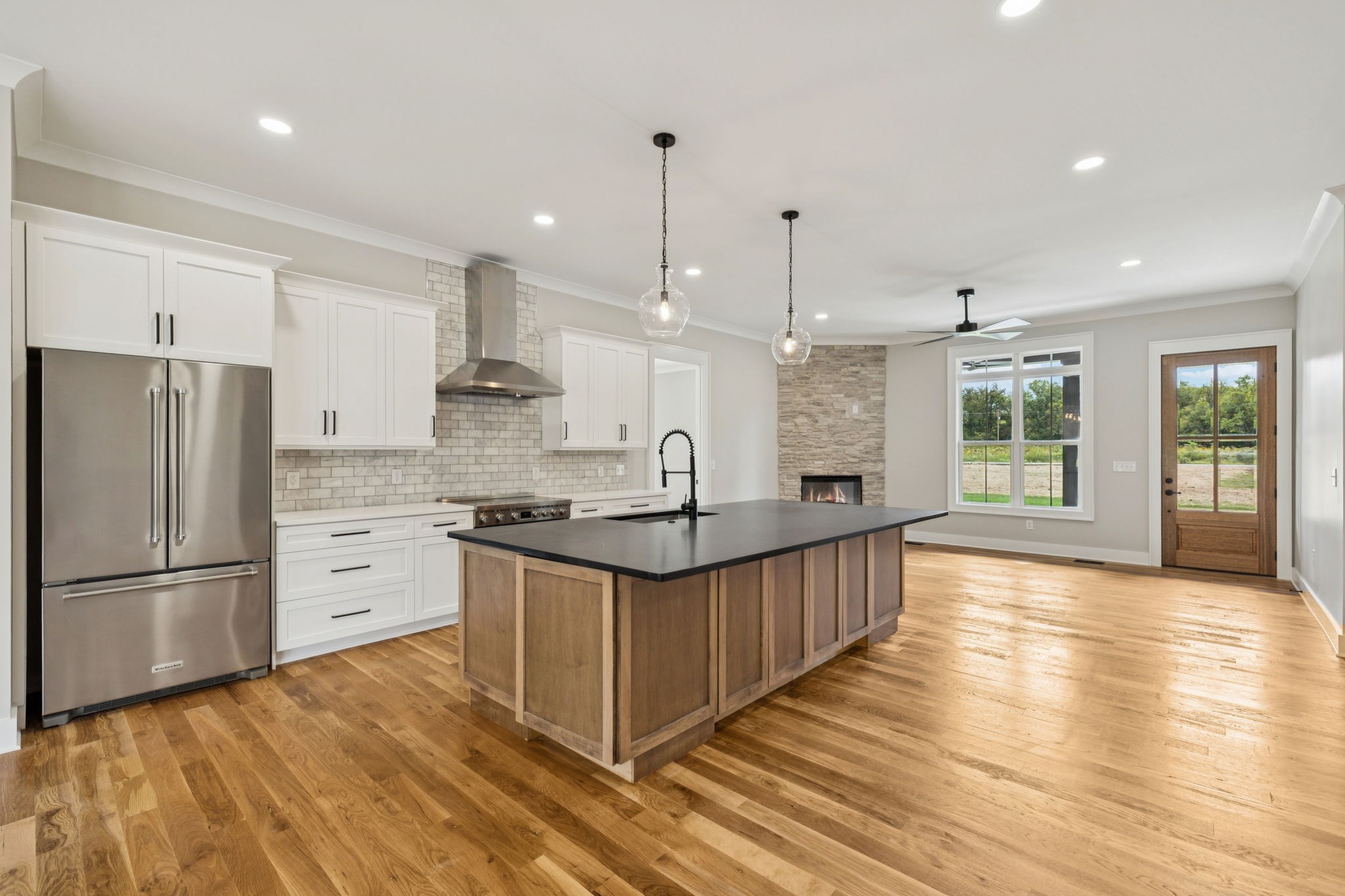 8297 12 Corners Road Lascassas, TN 37085 - Photo 12 of 63 a kitchen with stainless steel appliances granite countertop a stove a sink a refrigerator and white cabinets with wooden floor