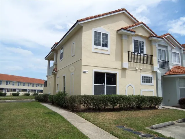 a view of a white house with a yard and potted plants