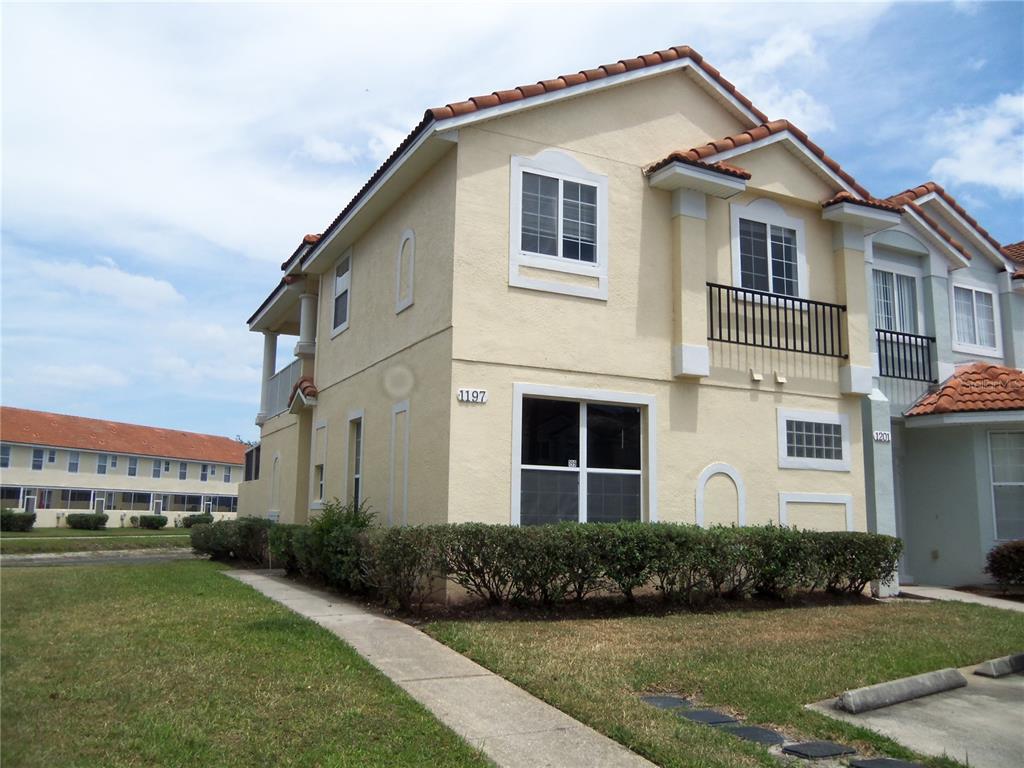 a view of a white house with a yard and potted plants