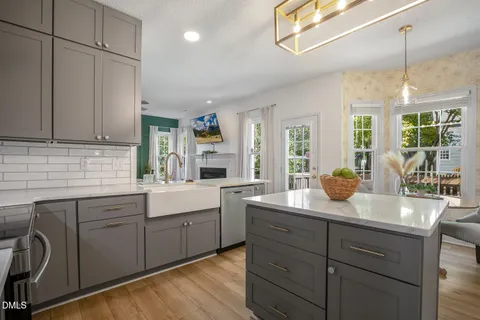 a kitchen with stainless steel appliances a refrigerator a sink a dining table and chairs