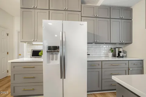 a kitchen with a sink and a stove with white cabinets