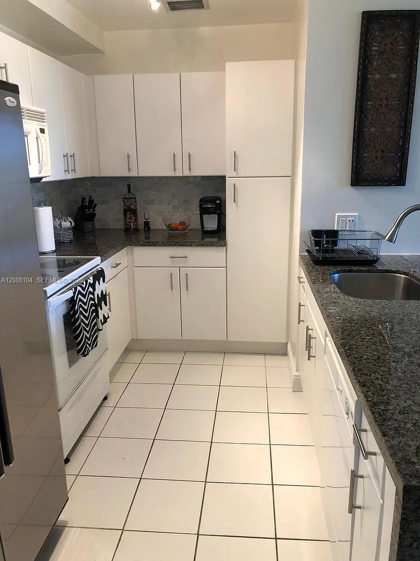 2400 Southwest 27th Avenue, Unit 304 Miami, FL 33145 - Photo 4 of 18 a kitchen with a sink a stove and cabinets