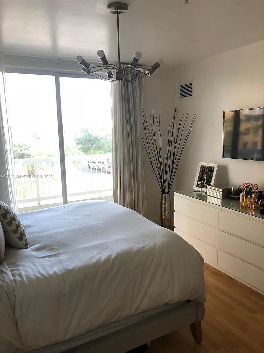 2400 Southwest 27th Avenue, Unit 304 Miami, FL 33145 - Photo 8 of 18 a bedroom with a bed and a flat tv screen