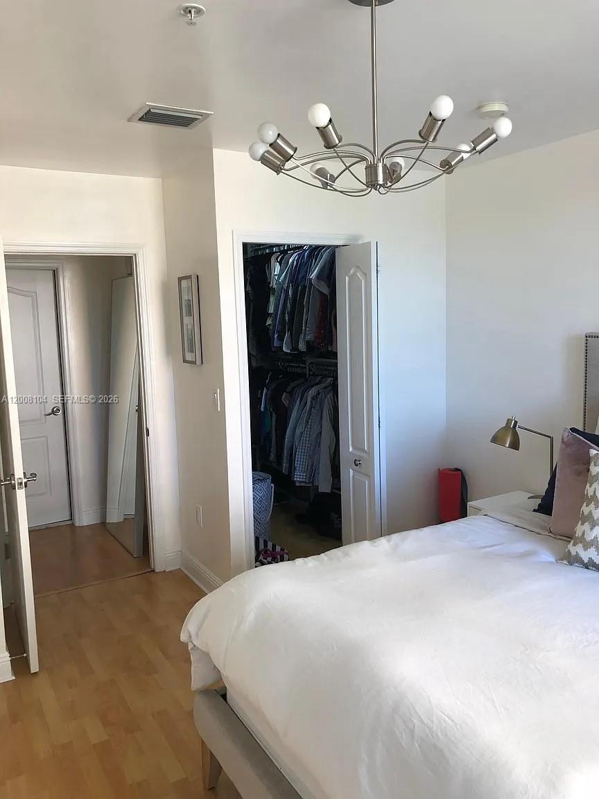 2400 Southwest 27th Avenue, Unit 304 Miami, FL 33145 - Photo 9 of 18 a bedroom with a bed and a chandelier