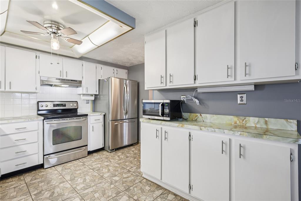 3548 Darlington Road Holiday, FL 34691 - Photo 14 of 32 a kitchen with stainless steel appliances granite countertop a sink a stove a refrigerator and white cabinets