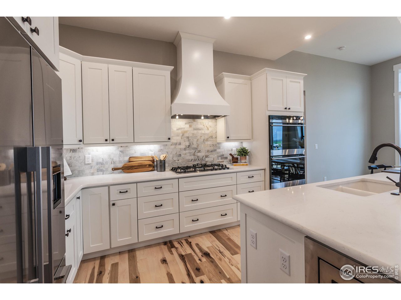 1293 Burt Avenue Berthoud, CO 80513 - Photo 17 of 40 a kitchen with granite countertop white cabinets and stainless steel appliances