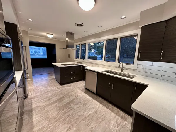 a large kitchen with stainless steel appliances granite countertop a sink stove and wooden cabinets