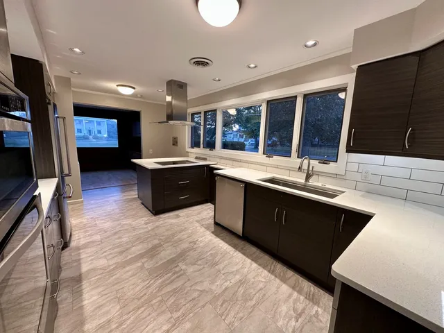 a large kitchen with stainless steel appliances granite countertop a sink stove and wooden cabinets