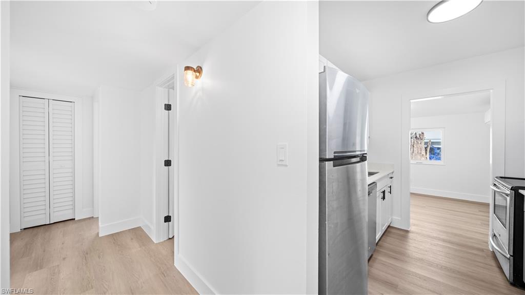 105 Oregon Road North Lehigh Acres, FL 33936 - Photo 5 of 17 Hallway with light wood-style floors and baseboards