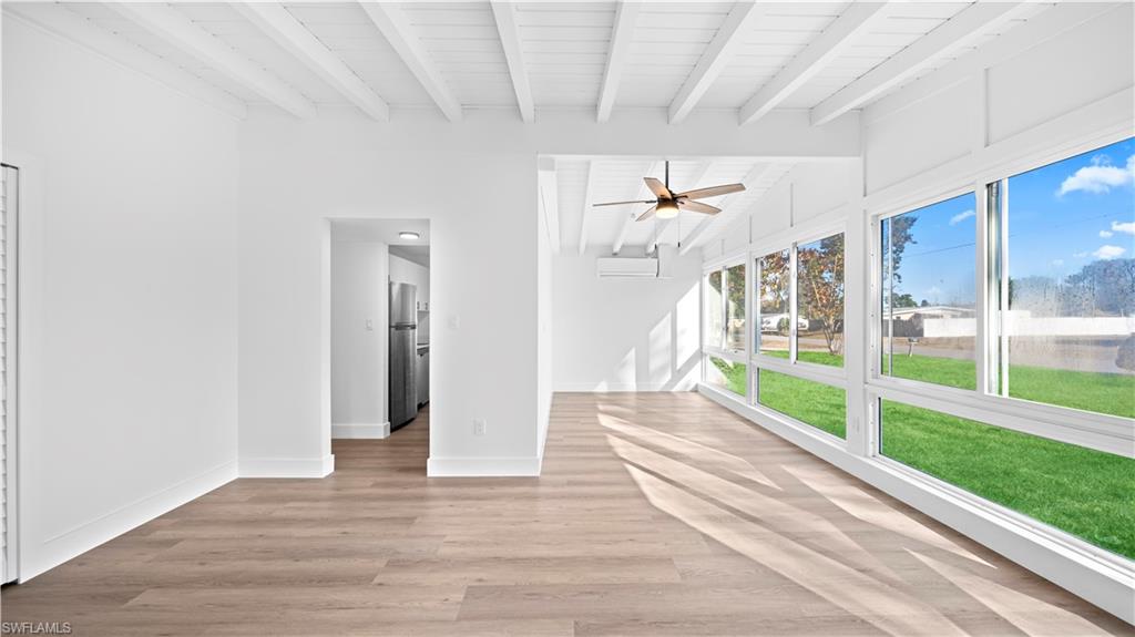 105 Oregon Road North Lehigh Acres, FL 33936 - Photo 6 of 17 Unfurnished living room featuring lofted ceiling with beams, ceiling fan, light wood finished floors, and wooden ceiling