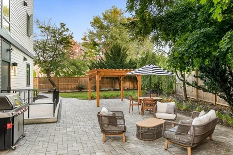 a view of a patio with couches table and chairs under an umbrella