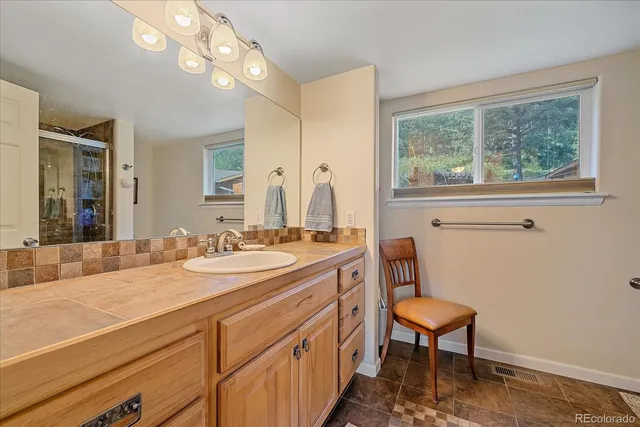 a bathroom with a sink a chair and a large mirror