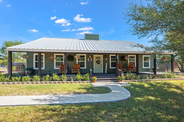 a front view of a house with swimming pool and porch with furniture