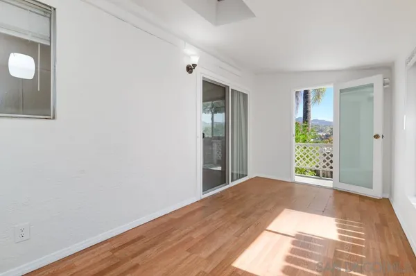 an empty room with wooden floor and a ceiling fan