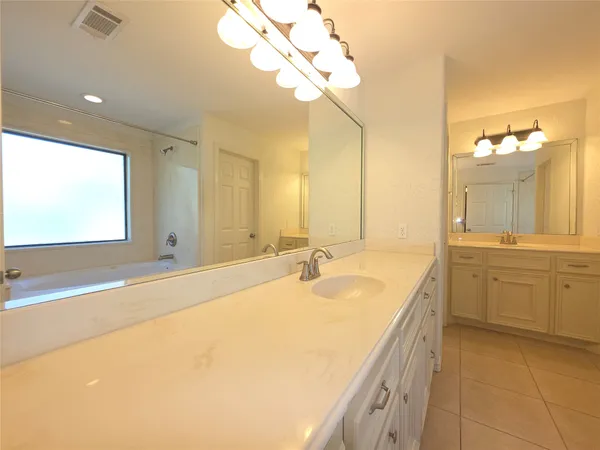 a spacious bathroom with a granite countertop sink a mirror and a bathtub
