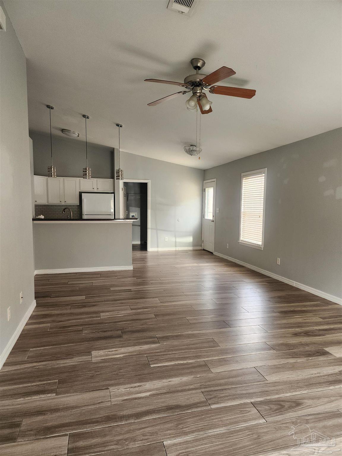 7447 Harvest Village Court Navarre, FL 32566 - Photo 16 of 27 a view of a room with kitchen island stainless steel appliances wooden floor and window
