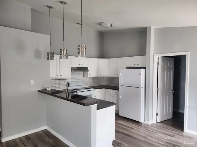 a kitchen with a sink a refrigerator a stove and white cabinets