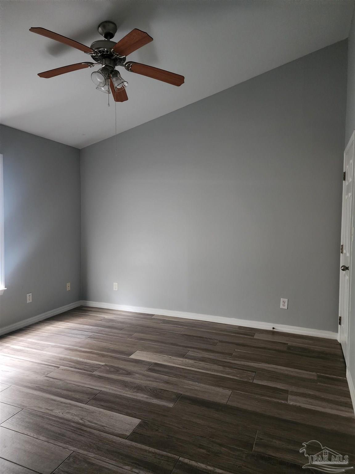 7447 Harvest Village Court Navarre, FL 32566 - Photo 24 of 27 a view of an empty room with wooden floor and a ceiling fan