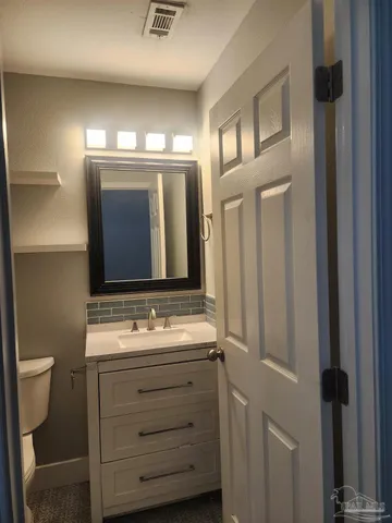 a bathroom with a sink mirror vanity and toilet