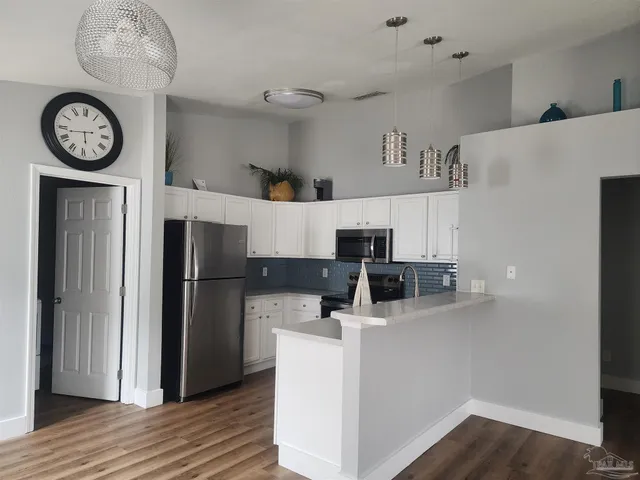 a view of a kitchen with fridge and wooden floor