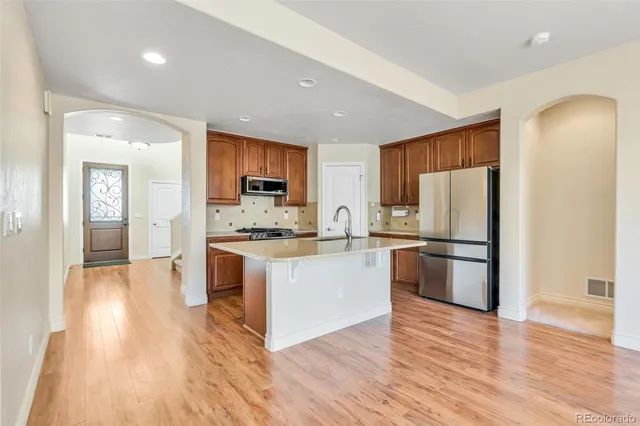 a large kitchen with a center island wooden floor stainless steel appliances and windows
