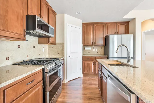 a kitchen with stainless steel appliances granite countertop a stove a sink and a refrigerator