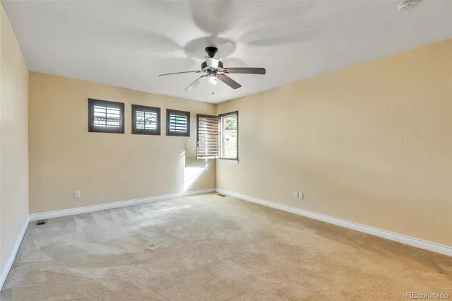 an empty room with windows and fan chandelier fan