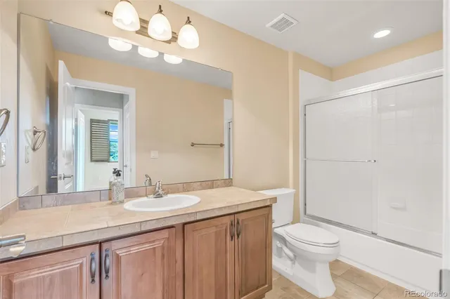 a bathroom with a granite countertop sink a toilet and a mirror