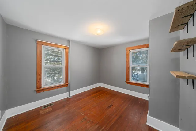a view of an empty room with window and wooden floor
