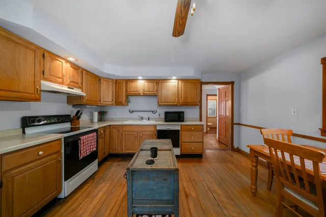 a kitchen with stainless steel appliances granite countertop a stove a sink dishwasher and a refrigerator with wooden floor