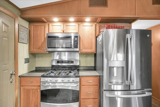a kitchen with stainless steel appliances granite countertop a refrigerator a stove and a sink with wooden floors