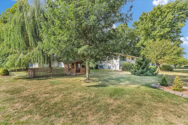 a view of a small house with large trees and wooden fence