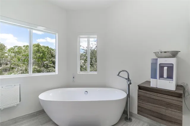 a white bath tub sitting in a bathroom next to a window