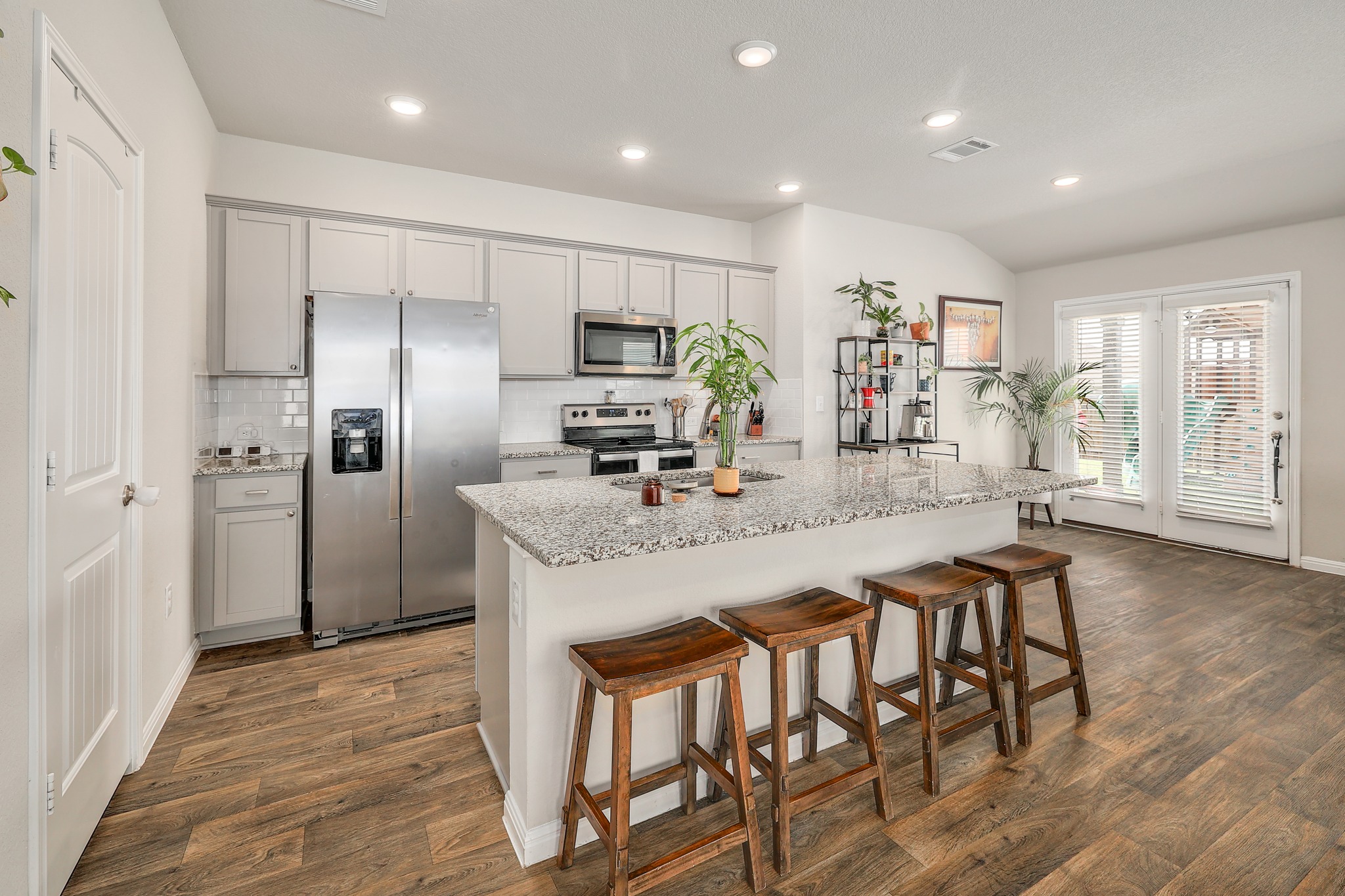 413 Hunter Loop Bertram, TX 78605 - Photo 11 of 27 A vibrant kitchen features a central island with breakfast bar seating, stainless steel appliances, and outdoor access.