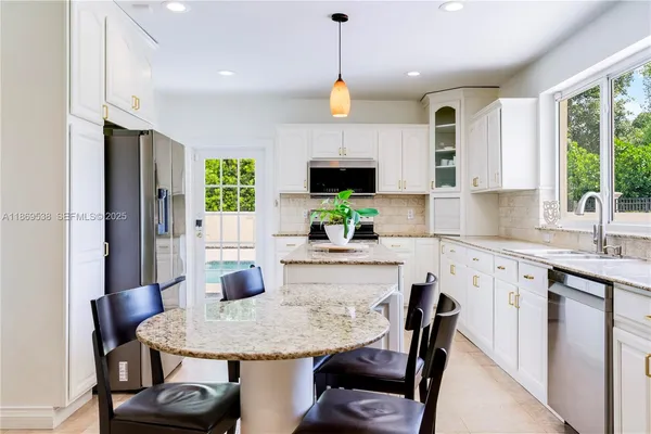 a kitchen with stainless steel appliances granite countertop a kitchen island hardwood floor sink stove dining table and chairs