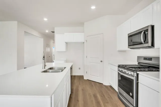 a kitchen that has a microwave a stove and white cabinets