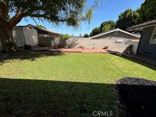 a view of a backyard with lawn chairs under an umbrella