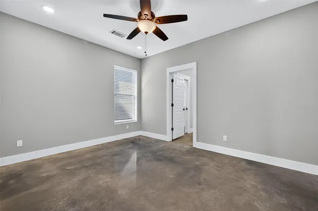 an empty room with windows and fan